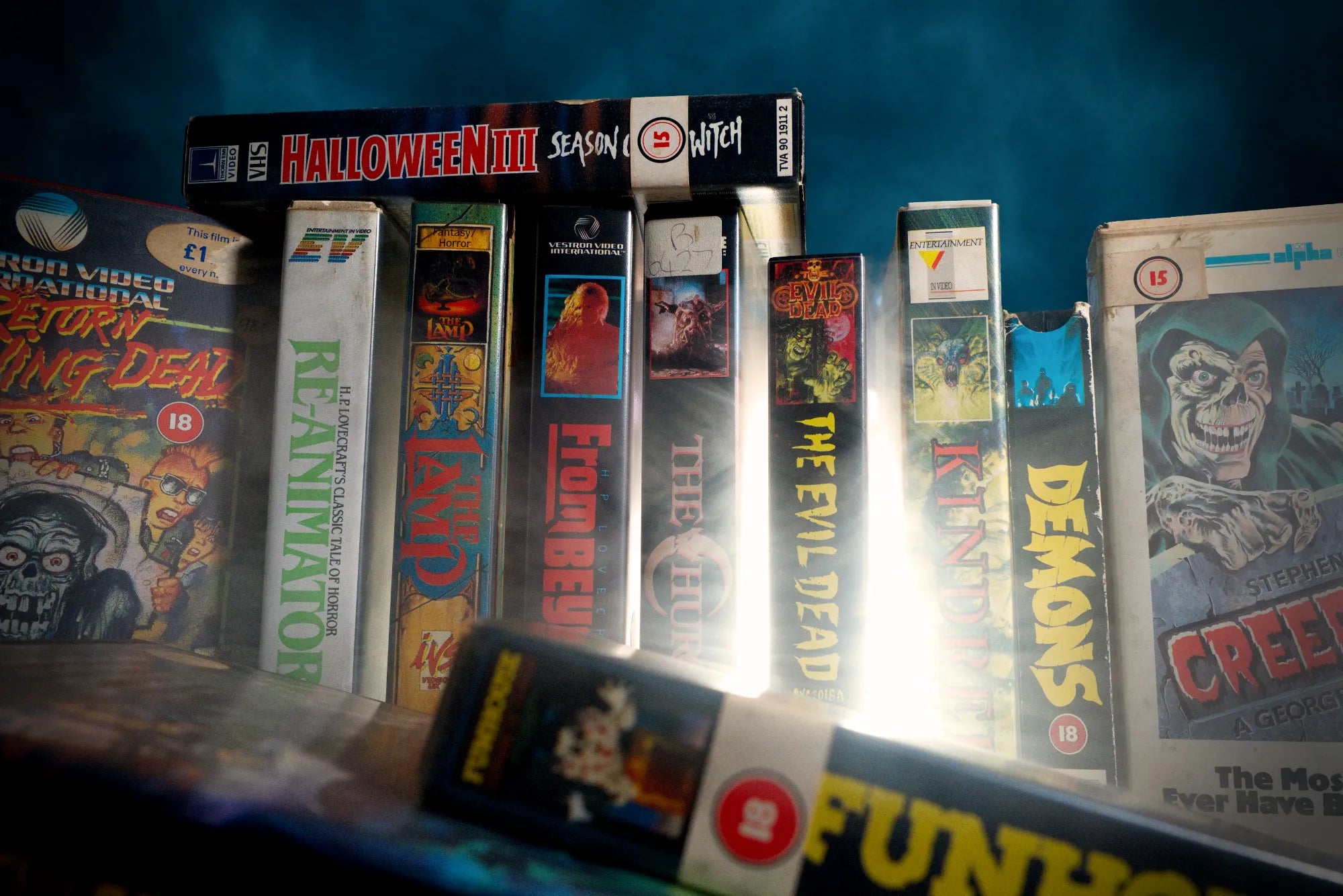 Retro horror VHS collection with foggy blue background used to illustrate the origin story of Splatter Caps.